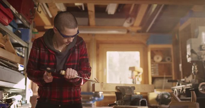 Young woman working with hammer and carving