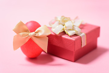 Red Easter egg and gift box on pink background