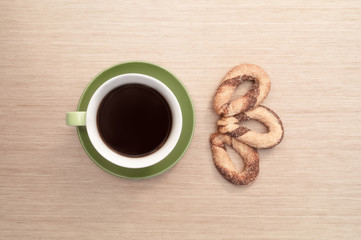 Green cup of coffee on the background of the table and biscuit. View from top