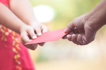 Parent give money in  red envelope to little child girl for celebrate in Chinese New Year