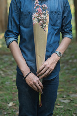 half body of man in blue jean shirt hand hold flower