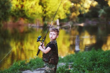 A handsome boy holding a fishing rod .Small fisherman on the river