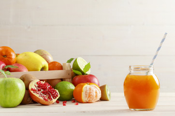 A glass of juice with a straw from different fruits