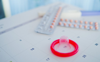 Fototapeta premium condom with contraceptive and pregnancy test on calendar, Birth control pill, safe sex, healthcare concept