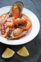 Closeup of a white plate with french byabes or fish soup, selective focus, studio shot