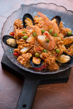 Portion of spanish seafood paella with mussels, tiger shrimps, calamari, green peas and red bell pepper, selective focus