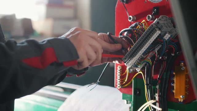 Electrician's hands installing energy system on machinery industry
