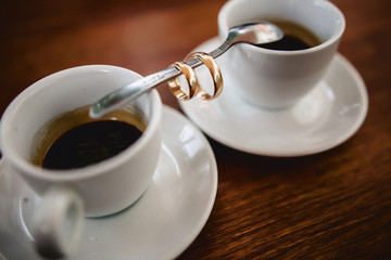 wedding bouquet and coffee with the wedding rings on the table