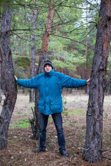 A rural guy posing in a pine forest in the autumn time.