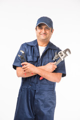 Indian plumber at work with Pipe wrench or plumbing spanner, standing isolated over white background
