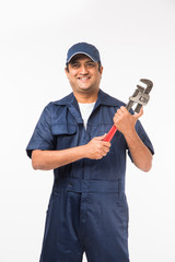 Indian plumber at work with Pipe wrench or plumbing spanner, standing isolated over white background

