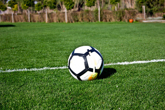 White soccer ball on a green grassy football field