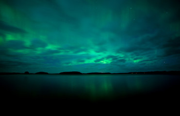 Fototapeta na wymiar Northern lights dancing over calm lake. Farnebofjarden national park in Sweden