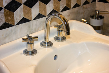Shiny clean sink and a faucet in the marble room