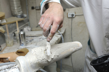 Worker applies special coating on wooden blank for further manufacturing prosthesis