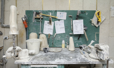 Wooden blanks, Bench Vices, pots and tools placed on a work table for manufacturing artificial limbs