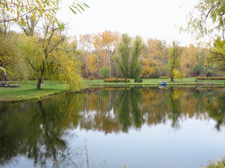 Fototapeta na wymiar Autumn landscape with colorful forest, lake, reflection and a boat