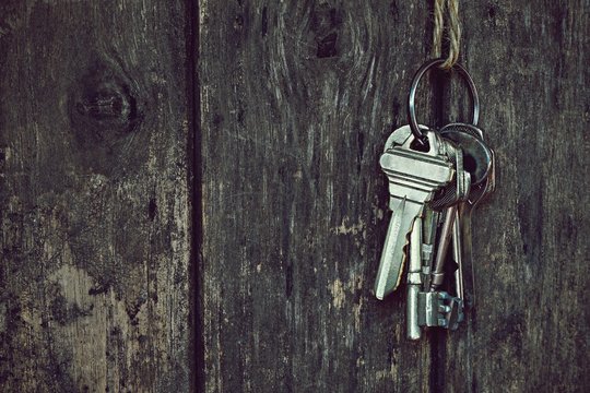 Key chain hanging with wood fence texture background in vintage tone