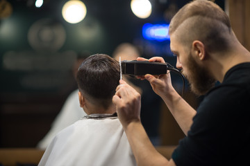 the young man the hairdresser cuts the schoolboy in hairdressing salon