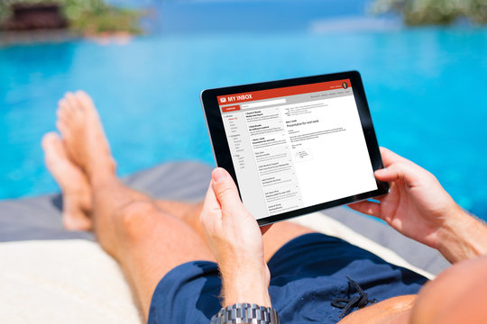 Man reading mail on tablet while on vacation