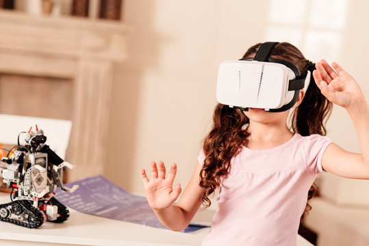 Favorite leisure activity. Waist up shot of a little girl with ponytails gesturing while wearing a virtual reality goggles and playing at home.