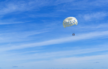 Skydiver on white parachute in sunny blue sky. Active lifestyle. Extreme sport.
