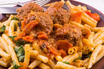 Macaroni with meatballs in tomato sauce with vegetables close-up