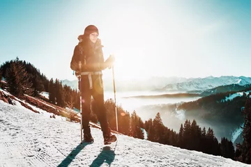 Foto auf Acrylglas Wintersport Woman hiking along a snowy mountain road in winter