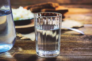 a glass of vodka on a wooden table.