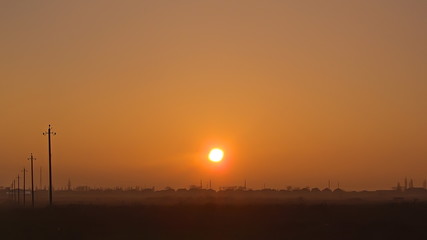 Obraz premium the setting sun over the roofs of houses. a haze over the field. natural background.