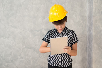 A boy wearing a yellow safety helmet are working with a digital tablet..