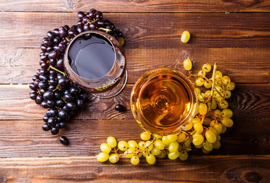 Image of two glasses with juice, grape, on wooden table,