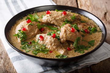 Chicken in spicy walnut sauce and pomegranate close-up in a bowl. horizontal