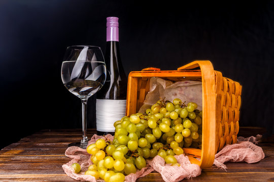 Picture of empty wine glass, grapes of green on wooden basket on table