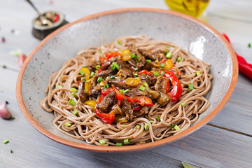 Stir fry from chicken hearts, paprika, onions and buckwheat noodles