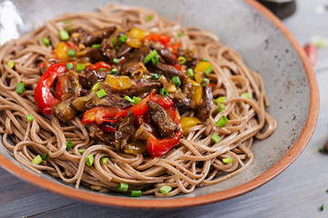 Stir fry from chicken hearts, paprika, onions and buckwheat noodles
