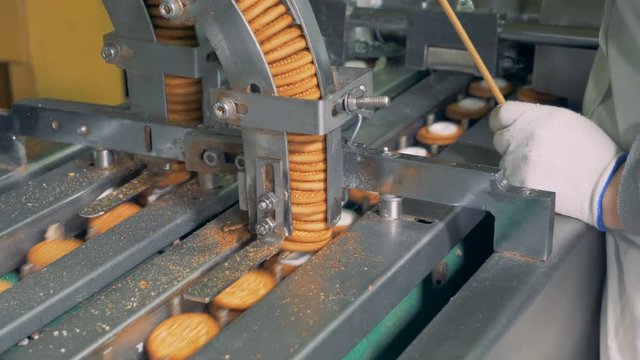 Process of making biscuits by a factory machine. Worker controlls the production process.