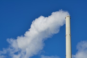 Smoking chimney against blue sky