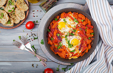 Fried eggs with pieces of pumpkin, red onions and tomatoes. Tasty breakfast. View from above