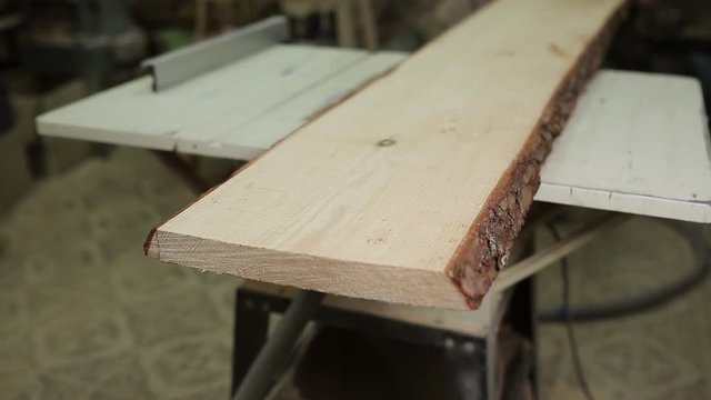 A man cuts a huge wooden Board with a stationary circular saws