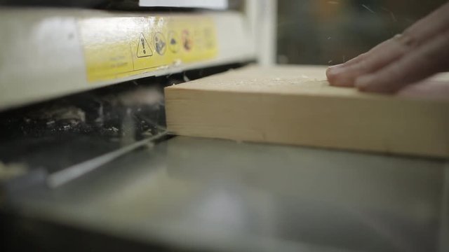 Carpenter planing of board with electric wood planer tool