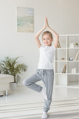 Fototapeta na wymiar beautiful little child practicing yoga in tree pose