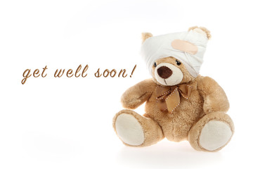 Teddybär mit verbundenem Kopf und dem Spruch "get well soon" nebenstehend