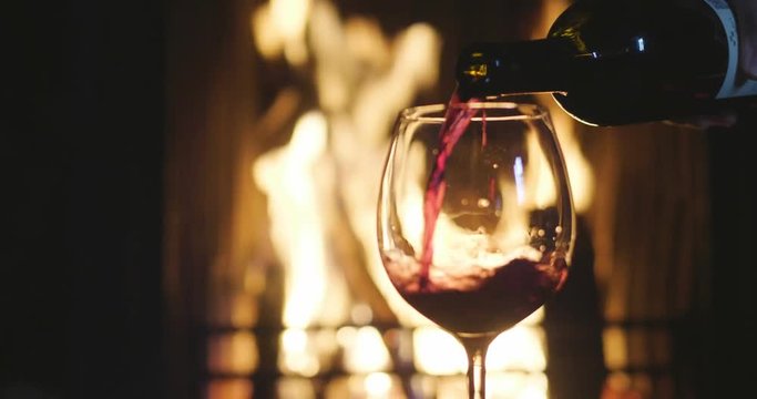 In winter, before the fireplace, is poured, tasted red wine in a glass. Concept of: relax, restaurant, wine, somelier.