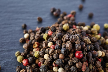 Top view on black, red and white peppercorns isolated on dark background, shallow depth of field.