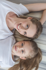 top view of mother and daughter looking at camera while relaxing