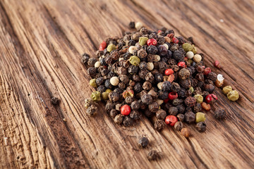 Top view on black, red and white peppercorns isolated on wooden background, shallow depth of field.