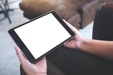 Mockup image of hands holding black tablet with blank white desktop screen