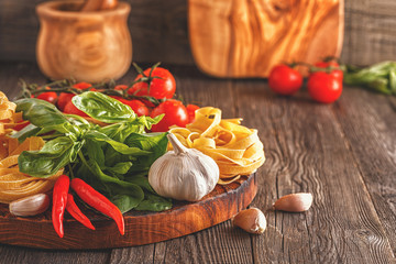 Products for cooking - pasta, tomatoes, garlic, pepper, and basil.