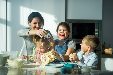 Mother and three children prepare something from the dough.